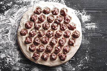 Handmade homemade dumplings on a metal tray on a wooden background with flour. Diy meat dumplings