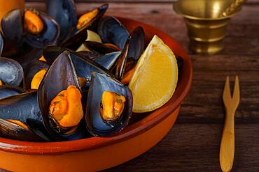 Steamed mussels with lemon in clay pot with metal mortar and pepper shaker