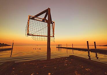 Wooden pier by the sea, sunset at water, orange sky