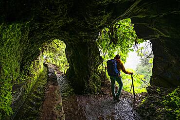 Hiker in a tunnel at PR9 Levada do Caldeirao Verde, Madeira, Portugal, Europe