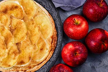 Sweet Tarte Flambee or Flammkuchen from German-French Alsace border region, a baked pie similar to a thin pizza topped with apple slices, sugar and cinnamon