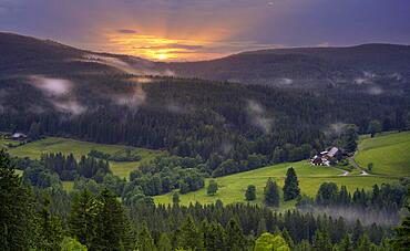 Some farms, surrounded by meadows and forest, in the evening after a thunderstorm, with some deep clouds, at sunset, Black Forest, Baden-Wuerttemberg, Germany, Europe