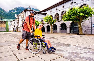 A disabled person in a wheelchair walking through the town square with a friend