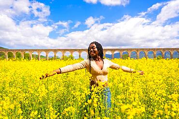 Lifestyle, enjoying nature in freedom, portrait of a black ethnic girl with braids, in a field of yellow flowers