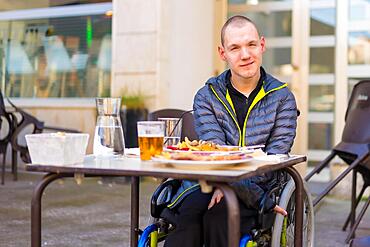 A disabled person in a wheelchair in a restaurant waiting to eat