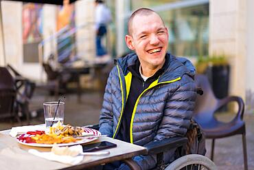 Portrait of a disabled person in a wheelchair in a restaurant smiling and having fun