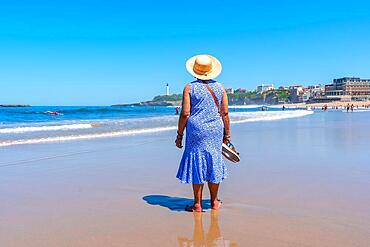 An elderly woman walking on the beach, South West resort town, Biarritz, Lapurdi. France