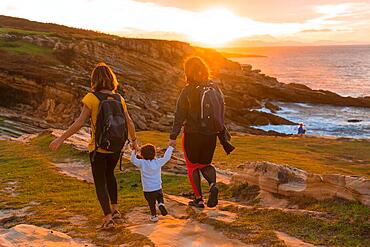 Lgbt couple of women with a child walking in the sunset on the coast by the sea, family lifestyle