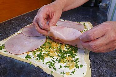 Swabian cuisine, preparing hearty snail pasta, topping raw yeast dough, herbs, onions, sour cream, cooked ham, small hearty snail pasta, salty yeast pastry, yeast dough, baking, from the oven, typical Swabian reinterpreted, party pastry, finger food, appetisers for on the go, traditional cuisine, food photography, studio, mens hands, Germany, Europe