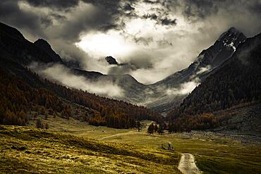 Way cross with path in autumnal mountain landscape with threatening cloudy sky, Pfossental, Merano, Vinschgau, South Tyrol, Italy, Europe