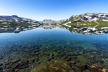 Reflection of partly snow-covered mountains in Lake Stavatn in Haukelifjell, Hardangervidda, Norway, Europe