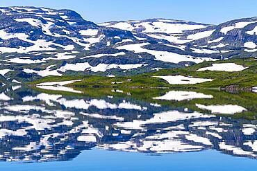 Reflection of partly snow-covered mountains in Lake Stavatn in Haukelifjell, Hardangervidda, Norway, Europe