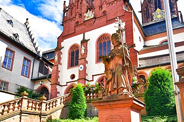 Aschaffenburg, Germany, July 2020: Statue of theologian Adolph Franz in front of historic Catholic curch called Kollegiatsstift St. Peter und Alexander or Stiftskirche, Europe