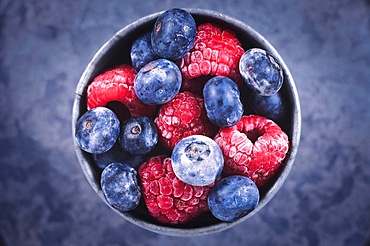 Top view of mixed blueberry and raspberry fruits in iron cup