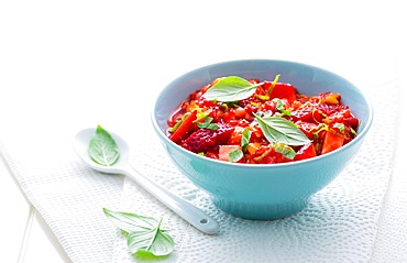 Fresh strawberry mango salsa garnished with Thai basil on white background