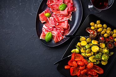 Assortment of appetizers and tapas with red wine on black background