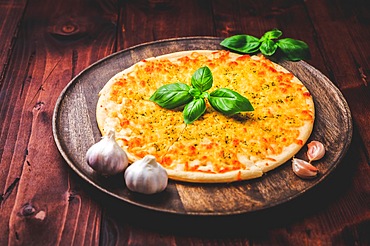 Pizza bread with garlic, cheese and basil on wooden background