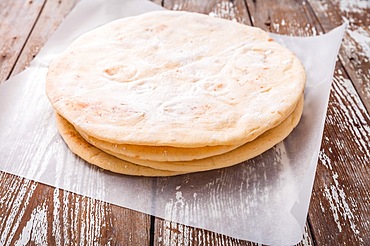 Flatbread, pita or pizza crust on wooden kitchen table