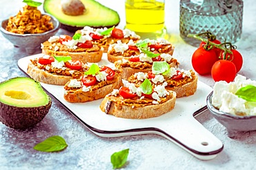 Bruschetta or open ciabatta sandwiches with avocado and tomato spread and feta cheese