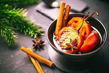 Christmas dessert - flamed tamarillo in hot wine punch with cinnamon and anise on black background