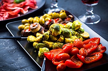 Assortment of appetizers and tapas with red wine on black background