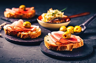 Roasted bread or open sandwich with garlic butter spread and serano ham and olive on dark background