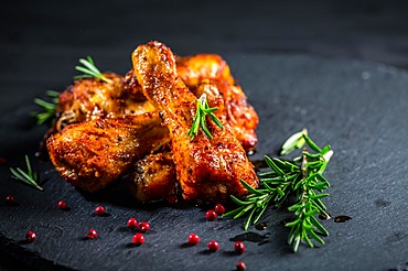 Oven baked chicken drumsticks with herbs and spicies on black background