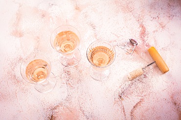 Three glasses of rose wine at wine tasting with bottle opener on pink marble background