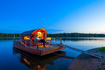 Man sitting in the blue hour on a houseboat, house raft, in front of the island Kiehnwerder, Breitlingsee, Brandenburg an der Havel, Havelland, Brandenburg, Germany, Europe