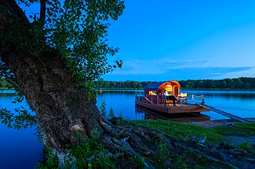 Man sitting in the blue hour on a houseboat, house raft, in front of the island Kiehnwerder, Breitlingsee, Brandenburg an der Havel, Havelland, Brandenburg, Germany, Europe