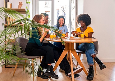 Friends at a breakfast with orange juice and muffins at home, together to celebrate good news