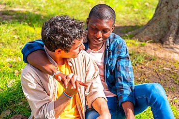 Couple of multiethnic gay men talking quietly in the park, lgbt concept