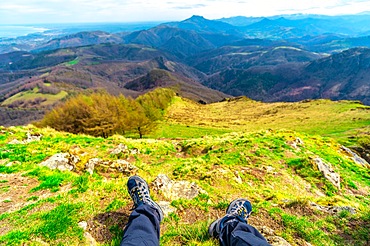 Mountain of Aiako Harria or Penas de Aya in the municipality of Oiatzun, Basque Country. Feet of mountaineer sitting on the trekking on the top