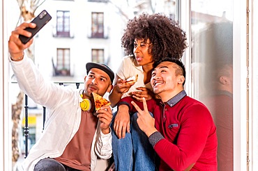 Friends eating pizza on the terrace at home, lunch or dinner, lifestyle, gastronomic concept, having fun taking a photo