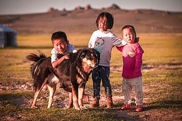 Local children play with their dog all day, Mongolia, Asia