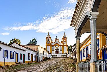 A quiet historic street in the city of Tiradentes in Minas Gerais with colonial houses and a baroque church in the background, Brasil