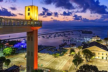 Lacerda elevator illuminated at dusk and with the sea and boats in the background in the city of Salvador, Bahia, Brasil