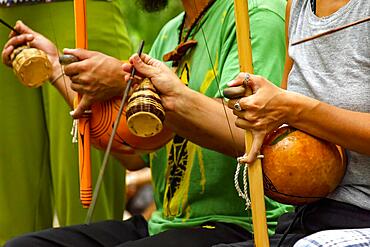 Musicians playing an Afro Brazilian percussion musical instrument called a berimbau during a capoeira performance in the streets of Brazil, Brasil