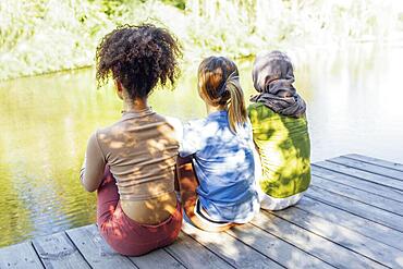 Rear view of multiracial young teen female friends resting in the park after sport training and having fun together. Diversity, sport and friendship concept