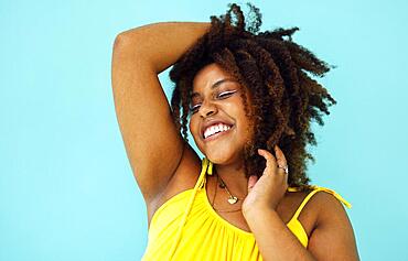 Beautiful bright joyful african woman in yellow dress in blue studio background