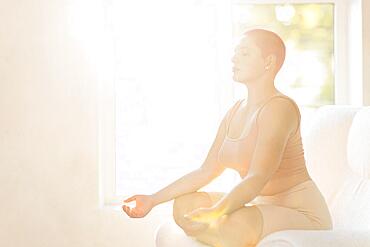 Happy young caucasian bald woman in light sunny room. Beautiful excited female model. Human emotions, facial expression concept. Keep calm, doing yoga