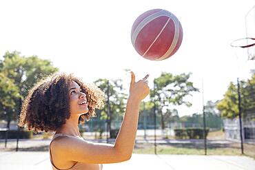 Mixed-race young smiling female outdoors and having fun. Stylish cool teen girl gathering at basketball court, playing basketball outdoors