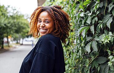 Close up photo of wavy hairdo charming cheerful dark skin person have good mood nice sightseeing weekend outdoors