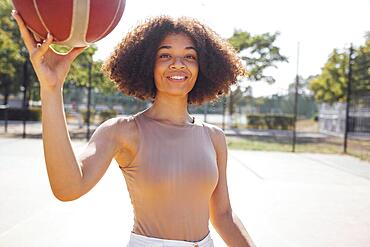 Mixed-race young smiling female outdoors and having fun. Stylish cool teen girl gathering at basketball court, playing basketball outdoors