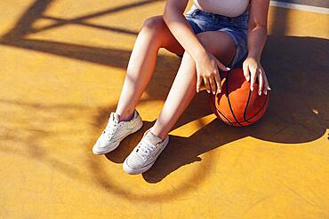 Mixed-race young smiling female outdoors and having fun. Stylish cool teen girl gathering at basketball court, playing basketball outdoors