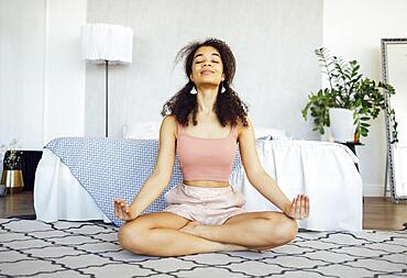 Meditation And Relaxation. Black Girl Doing Morning Yoga Sitting In Lotus Position Relaxing by Bed At Home. Healthcare and selfcare concapt