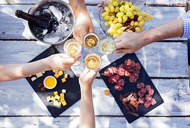 Happy people on the beach having a party, drinking and having a lot of fun in the sunset, they are wearing smart casual clothes and drink champagne