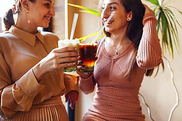 Happy young female friends having coffee break while relaxing at indoor cafe. Friendship concept