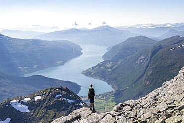 Hikers climbing to the top of Skala, view of mountains and fjord Faleidfjorden, Loen, Norway, Europe