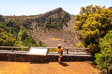 A young woman at the viewpoint of the Fireba volcano in La Llania park in El Hierro, Canary Islands. Next to El Brezal the humid forest